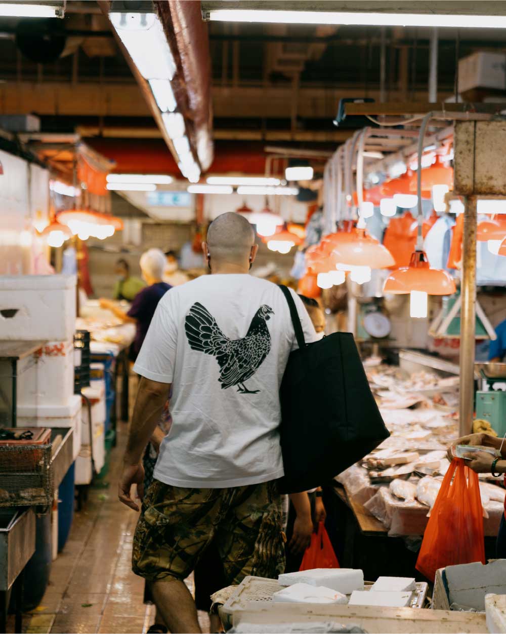 Chef Matt holds a black insulated alexander zip tote while walking through a open air market