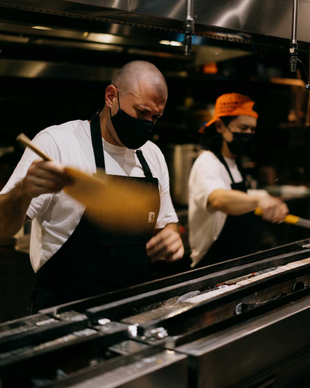 Chef Matt fans a narrow charcoal grill in his restaurant's kitchen